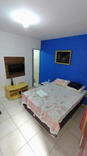 a bedroom with a large bed and a blue wall at Suites Solar dos Arcanjos Guaramiranga in Guaramiranga