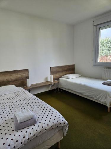 two beds in a room with a window at Maison ouvrière pour 8 personnes in Trignac