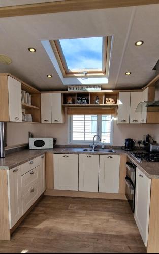 a kitchen with white cabinets and a skylight at Hampton's Retreat, Haven Church Farm in Pagham
