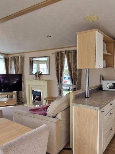 a living room with a couch and a tv at Hampton's Retreat, Haven Church Farm in Pagham