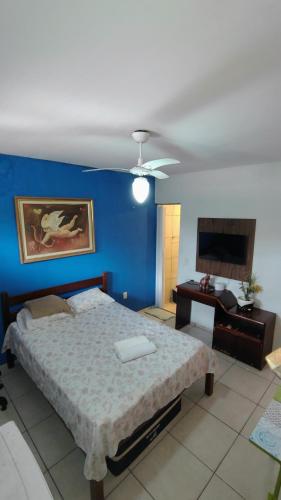 a bedroom with a bed with a blue wall at Suites Solar dos Arcanjos Guaramiranga in Guaramiranga