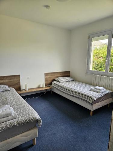 two beds in a room with a window at Maison ouvrière pour 8 personnes in Trignac
