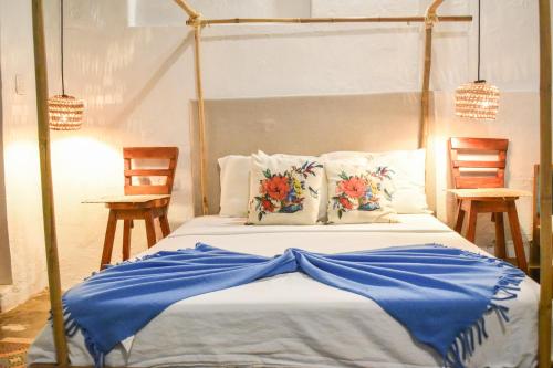Santa Cruz de MompoxにあるHostel Pueblito Magico Mompósの青いシーツと椅子が備わった天蓋付きベッドのある寝室