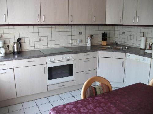 uma cozinha com armários brancos, um lavatório e um fogão em Ferienwohnung Am Bach em Rees