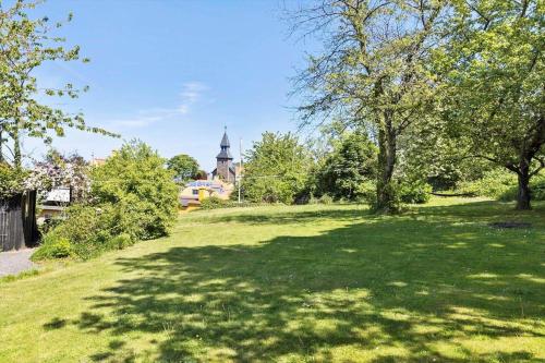 a green field with trees and a church in the background at 5606-Gudhjem-Holkavej-12 in Gudhjem