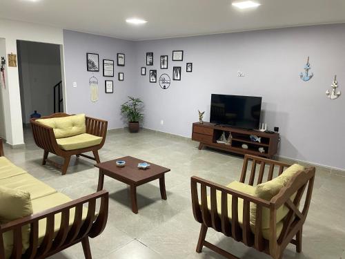 Una sala de estar con sillas, un televisor y una mesa. en Casa Valentina em Milagres - AL, en São Miguel dos Milagres