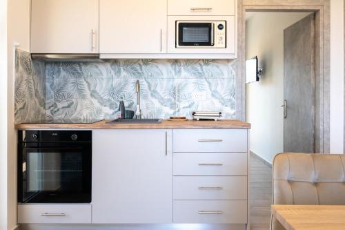 a kitchen with white cabinets and a microwave at Smiles Apartments With Panoramic View in Zipárion