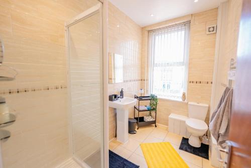 Un baño con ducha, inodoro y lavabo. en Spacious Modern & High Ceiling One Bedroom Apartment, en Cardiff