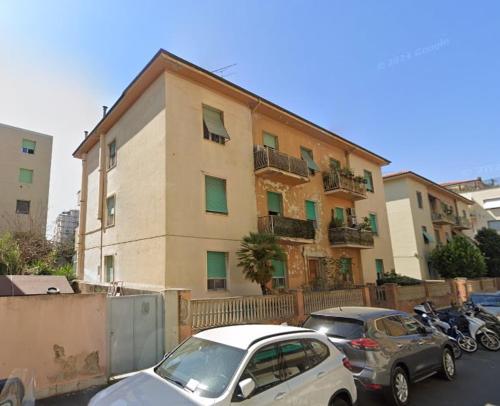 Un edificio con coches aparcados en un estacionamiento. en Appartamento Fabbricotti, en Livorno