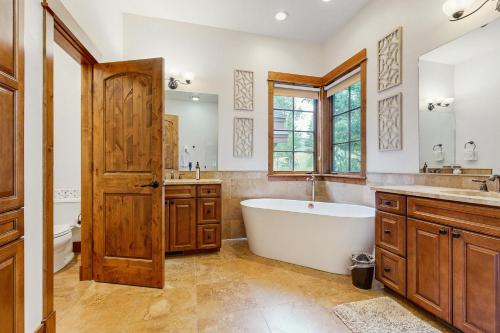 Un baño con bañera, lavabo y espejo. en Moose Hill 59, en Big Sky