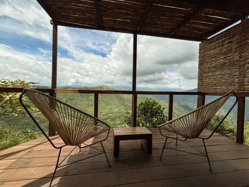 two chairs and a bench on a deck with a view at REFUGIO LA ROCA in Los Santos