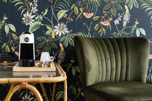 a green chair in front of a wall with floral wallpaper at B&B Maas en Heuvel Maastricht in Maastricht
