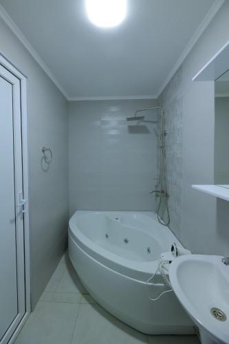 a white bathroom with a tub and a sink at Hotel Harmony Premium in Kutaisi