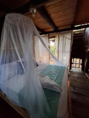 a bed with a mosquito net in a room at Mangle House Cabañas Ladrilleros in Buenaventura