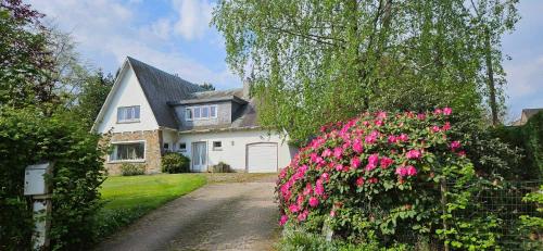 a white house with pink flowers in front of it at Marmouset in Theux
