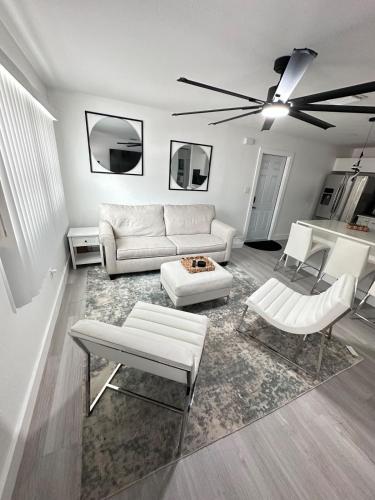 a living room with white furniture and a ceiling fan at Cozy Retreat Near Downtown Fort Myers in Fort Myers