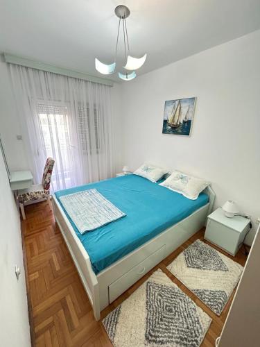 a bedroom with a bed with blue sheets and a window at Milenijum in Podgorica