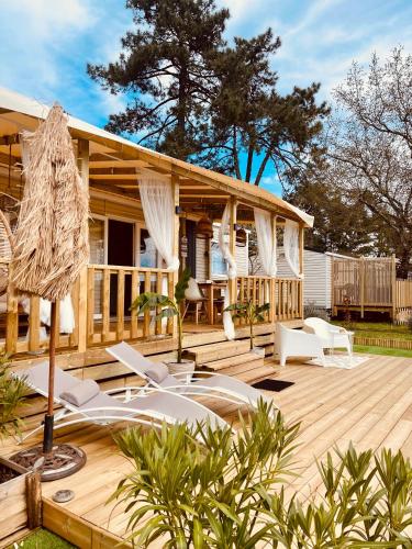 a wooden deck with white chairs and a house at Magnifique Mobil home avec vue in Lège-Cap-Ferret