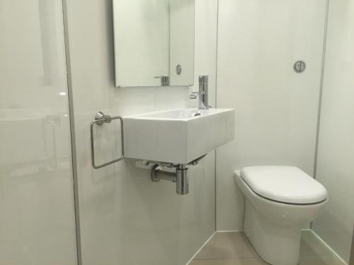 a white bathroom with a sink and a toilet at The Harbour Guest House in Irvine