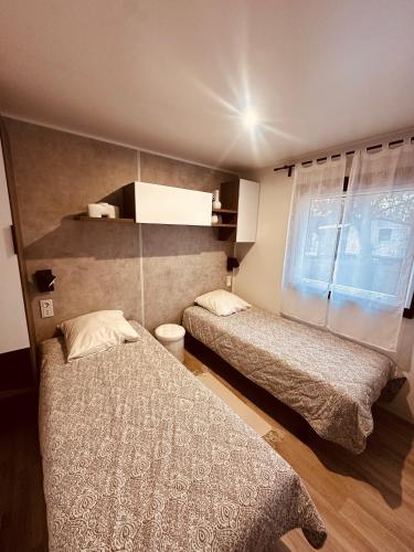 a bedroom with two beds and a window at Magnifique Mobil home avec vue in Lège-Cap-Ferret