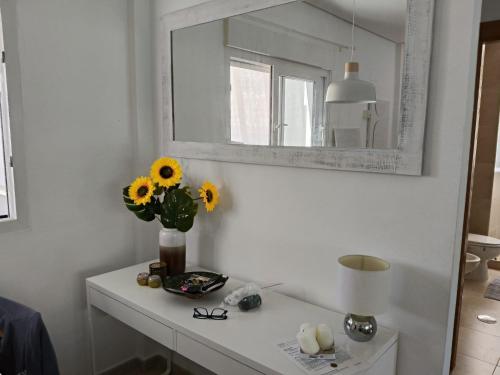 eine Vase mit Sonnenblumen auf einem weißen Tisch mit einem Spiegel in der Unterkunft La Torre Golf 3-Bed Villa- Heated Pool and Hot Tub in Las Armeras
