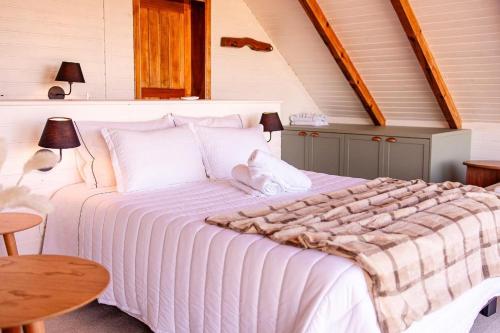a bedroom with a large white bed in a attic at Chalé cruzeiro do sul, hidromassagem, 2 min Thermas Machadinho-RS #2 in Machadinho