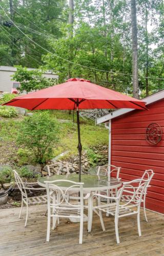 a table and chairs with a red umbrella on a deck at CanaanLand in Littleton