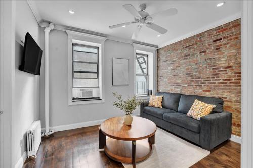a living room with a couch and a brick wall at Gramercy Apartment - 3BR 2BA Modern Central in New York