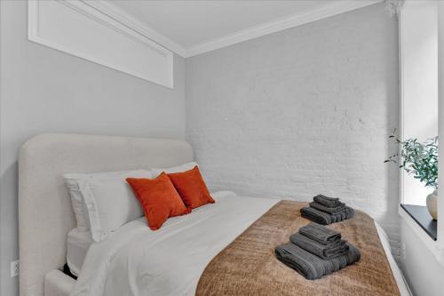 a white bedroom with a bed with orange pillows at Gramercy Apartment - 3BR 2BA Modern Central in New York
