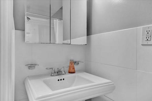 a white bathroom with a sink and a mirror at Gramercy Apartment - 3BR 2BA Modern Central in New York
