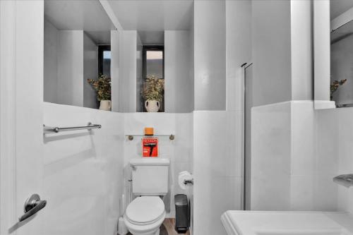 a white bathroom with a toilet and two mirrors at Gramercy Apartment - 3BR 2BA Modern Central in New York