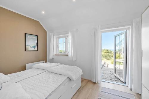 a white bedroom with a bed and a large window at 6727-Hasle-Udmarksvej-10 in Hasle