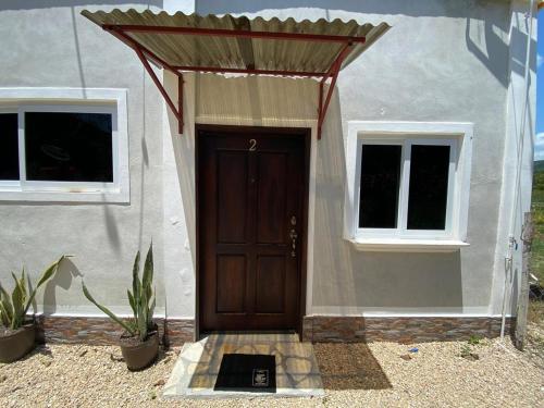 a house with a brown door and two windows at Habitaciones Cahui in El Remate