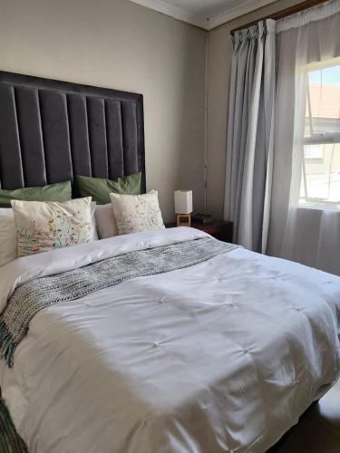 a large white bed in a bedroom with a window at Pearl palace in Polokwane