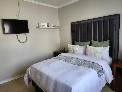 a bedroom with a large bed and a flat screen tv at Pearl palace in Polokwane