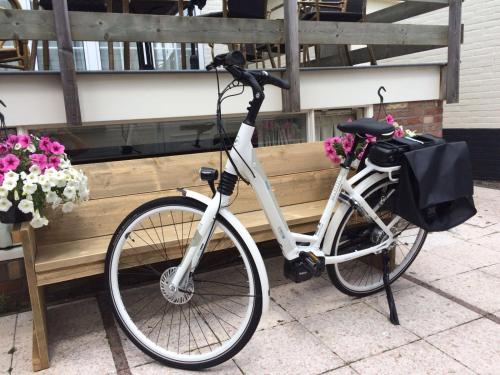 a bike parked next to a wooden bench with flowers at Hotel Stad en Land in Alkmaar