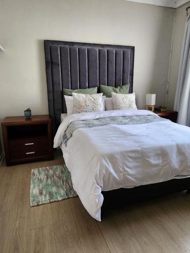 a bedroom with a large bed with a black headboard at Pearl palace in Polokwane