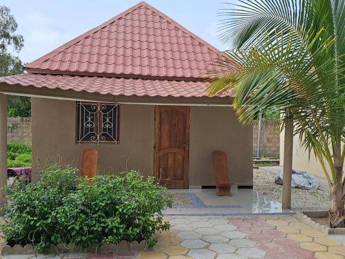 a small house with a red roof and a door at FARAFINA KEUR DAMEL Toubakouta in Toubakouta