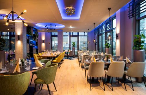 a restaurant with tables and chairs and windows at Leonardo Hotel Eschborn Frankfurt in Eschborn