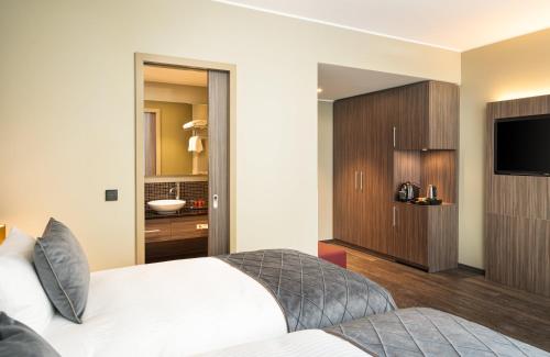 a hotel room with a bed and a television at Leonardo Hotel Eschborn Frankfurt in Eschborn