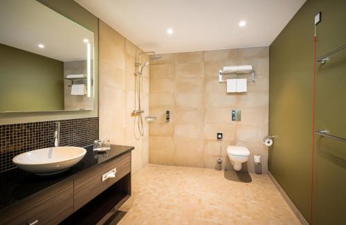 a bathroom with a sink and a toilet at Leonardo Hotel Eschborn Frankfurt in Eschborn