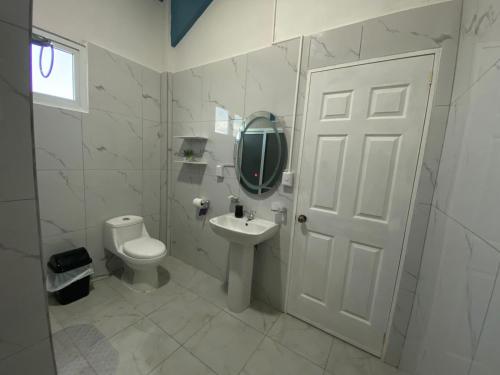 a bathroom with a toilet and a sink and a mirror at Habitaciones Cahui in El Remate