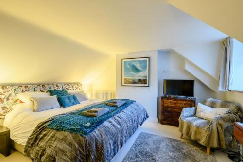a bedroom with a bed and a tv and a chair at Hemingford Cottage in Brancaster