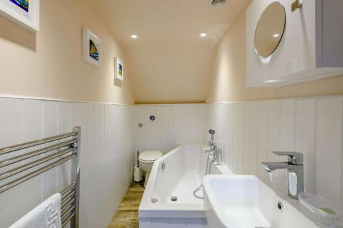a bathroom with a tub and a sink and a toilet at Hemingford Cottage in Brancaster