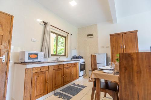 a kitchen with wooden cabinets and a table and a dining room at Kounous Self-Catering Apartments in La Réunion