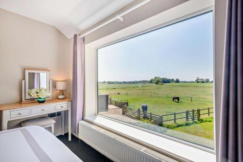 Swallows Return - Colkirk في Colkirk: غرفة نوم بها نافذة كبيرة مطلة على المراعي