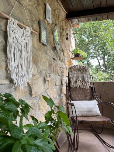 a rocking chair on a porch with a stone wall at A casa di Giovanni apartment in Albano di Lucania