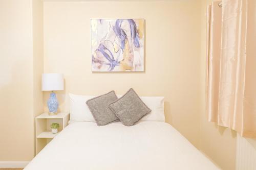 a bedroom with a white bed with two pillows at North London Holiday home, Driveway Parking, BBQ and Indoor Jacuzzi hot tub in Brimsdown Station