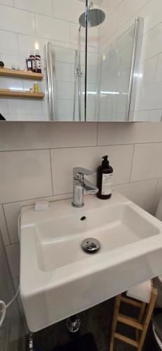 Un lavabo blanco en un baño con espejo. en Room best location Stockholm, en Estocolmo