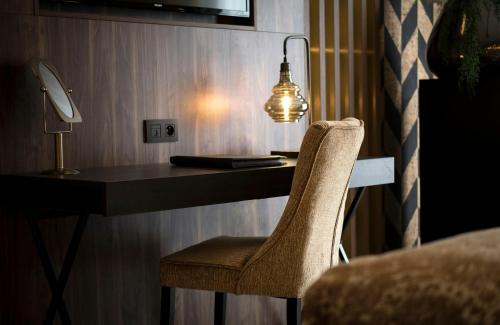 a desk with a chair and a lamp on it at Leonardo Hotel Antwerp The Plaza in Antwerp